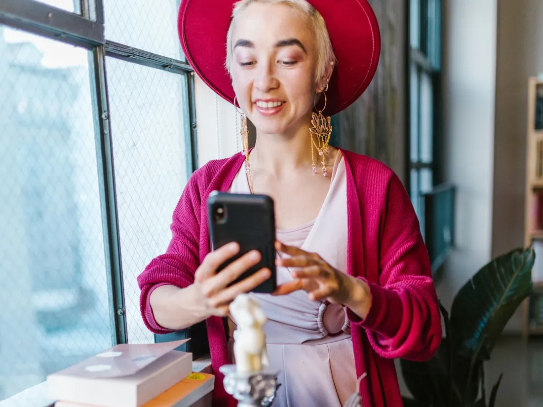 Commerçante en chapeau qui photographie ses bougies artisanales avec son téléphone dans sa boutique