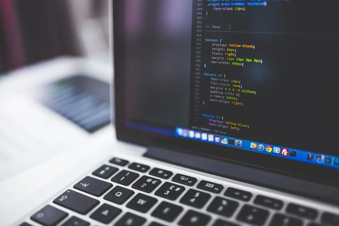 Écran d'ordinateur portable affichant du code HTML en gros plan, clavier au premier plan