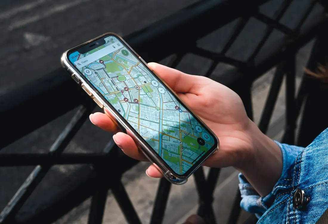 Main tenant un iPhone avec une carte de ville à l'écran