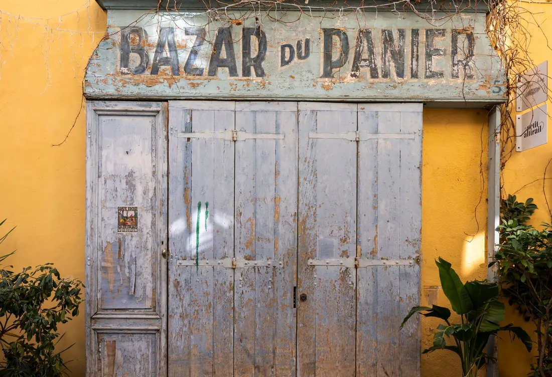 Porte fermée d'un ancien bazar au soleil, façade ocre à Marseille